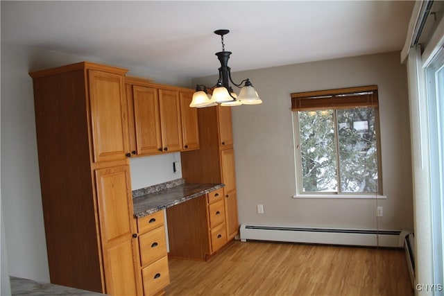 kitchen featuring dark stone counters, pendant lighting, a baseboard radiator, a notable chandelier, and light hardwood / wood-style floors