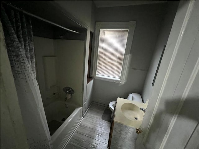 full bathroom with hardwood / wood-style flooring, toilet, washtub / shower combination, and sink