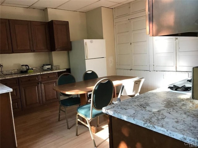 kitchen with white refrigerator, ventilation hood, light hardwood / wood-style flooring, and a drop ceiling