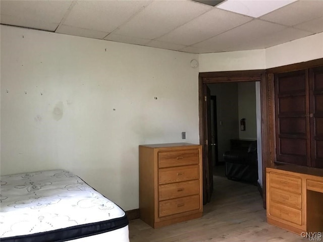 bedroom with a paneled ceiling and light hardwood / wood-style flooring