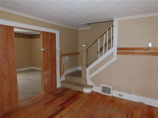 staircase with hardwood / wood-style floors and ornamental molding