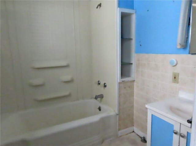 bathroom with bathing tub / shower combination, vanity, and tile walls