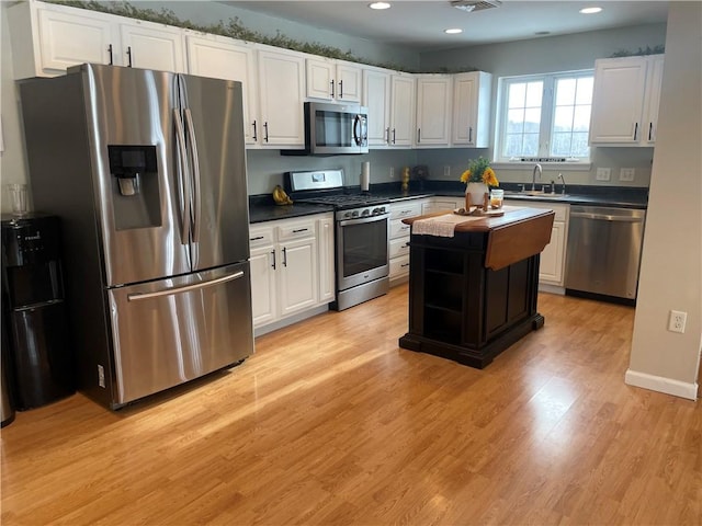 kitchen with light wood-type flooring, a center island, stainless steel appliances, and white cabinets