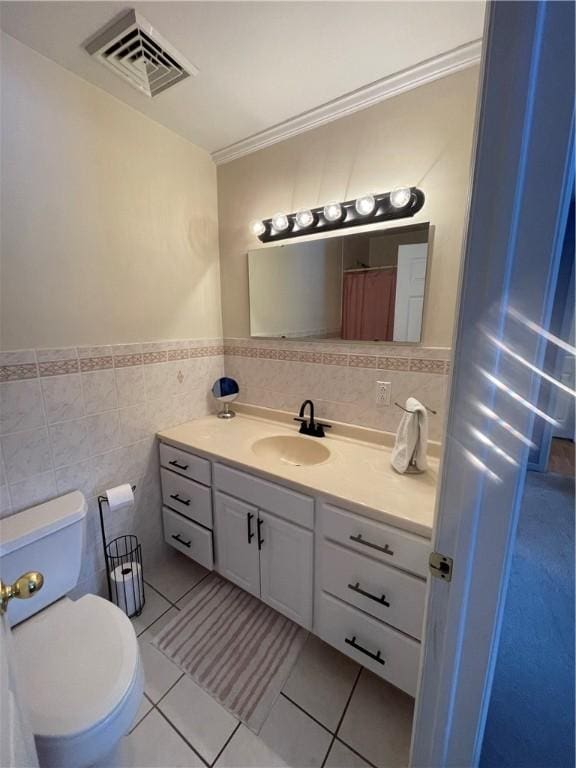 bathroom featuring toilet, vanity, tile patterned floors, and tile walls