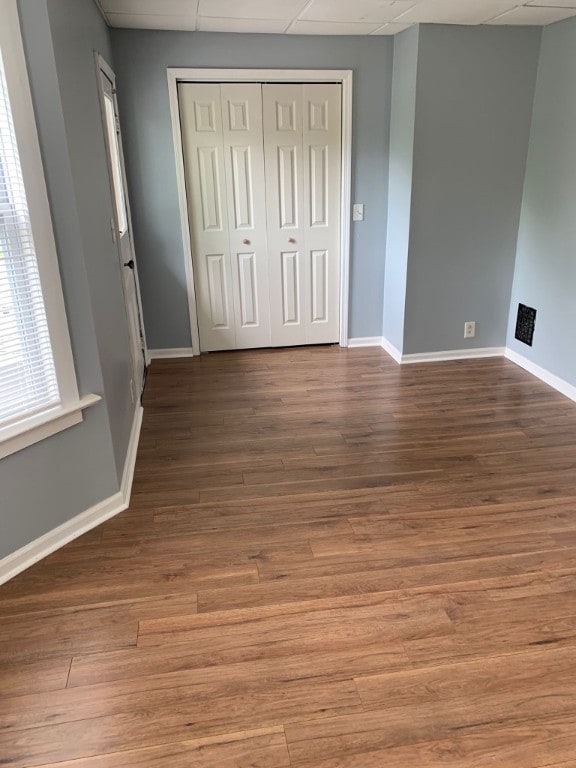 unfurnished bedroom featuring wood-type flooring, a closet, and a drop ceiling