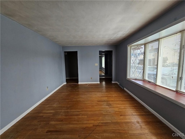 unfurnished room with dark hardwood / wood-style flooring