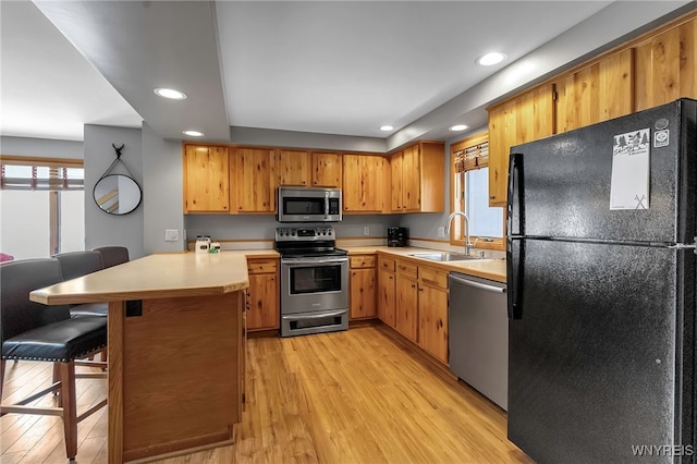 kitchen featuring a kitchen bar, appliances with stainless steel finishes, kitchen peninsula, and a healthy amount of sunlight