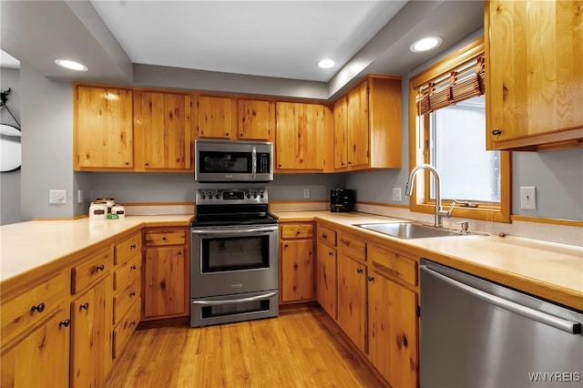 kitchen with sink, stainless steel appliances, and light wood-type flooring