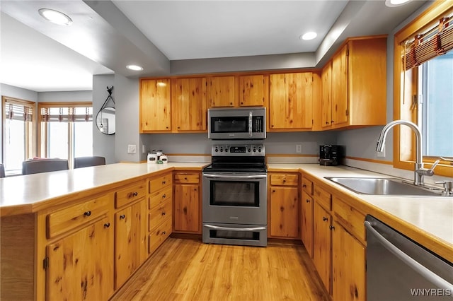 kitchen featuring kitchen peninsula, stainless steel appliances, light hardwood / wood-style floors, and sink