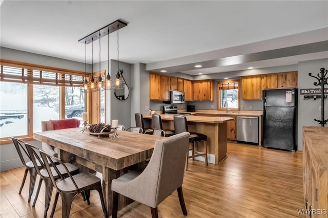 dining area with a notable chandelier, a healthy amount of sunlight, sink, and light hardwood / wood-style flooring