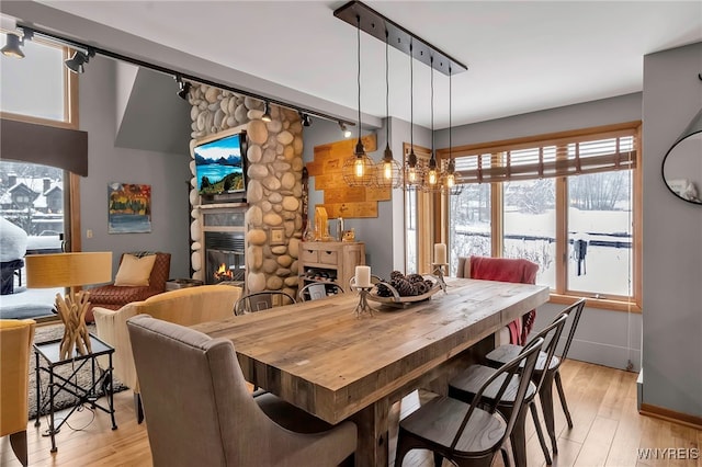 dining area featuring a fireplace, rail lighting, and light hardwood / wood-style floors