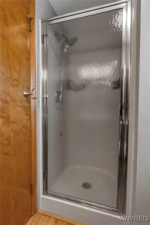 bathroom featuring hardwood / wood-style flooring and walk in shower