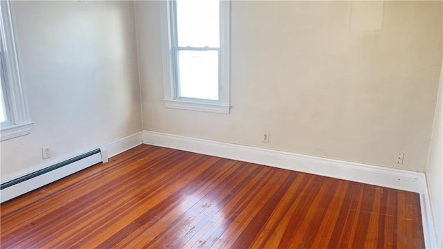 empty room featuring hardwood / wood-style floors and a baseboard heating unit