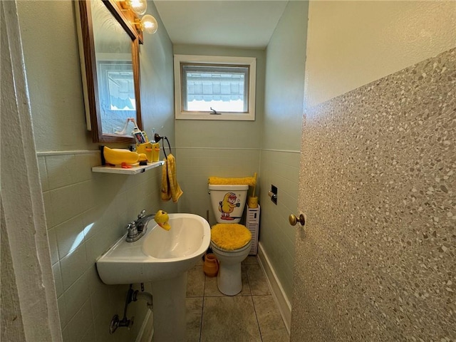 bathroom with tile patterned floors, sink, toilet, and tile walls