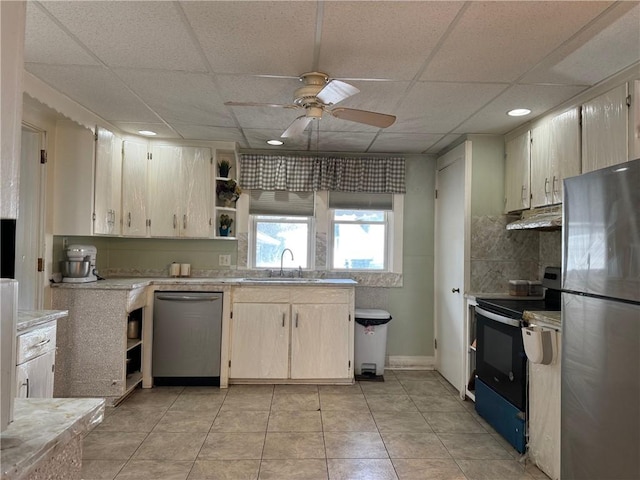 kitchen with a drop ceiling, sink, ceiling fan, light tile patterned floors, and stainless steel appliances