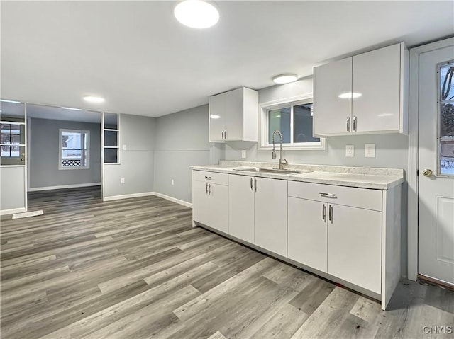 kitchen with light hardwood / wood-style flooring, white cabinetry, and sink