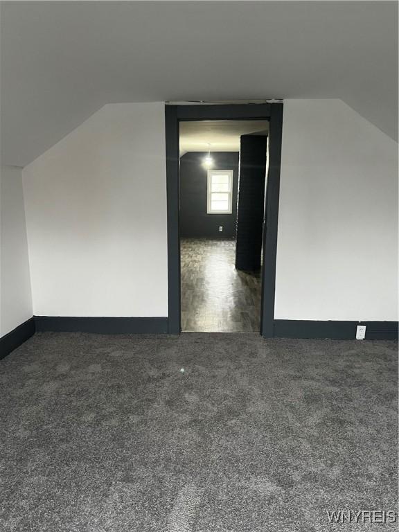 bonus room featuring dark carpet and lofted ceiling