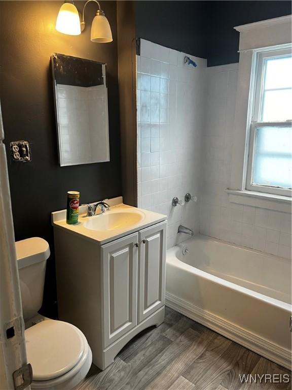 full bathroom with tiled shower / bath, toilet, vanity, and hardwood / wood-style flooring