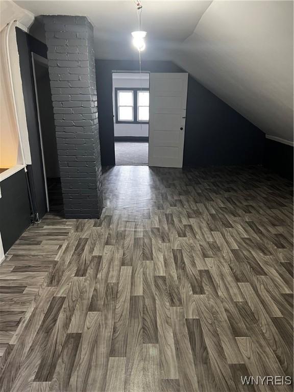 additional living space with dark wood-type flooring and lofted ceiling