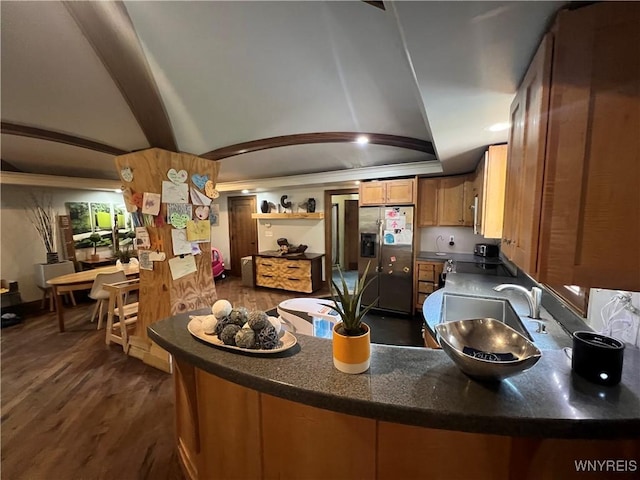 kitchen featuring sink, vaulted ceiling, stainless steel fridge, dark hardwood / wood-style flooring, and kitchen peninsula