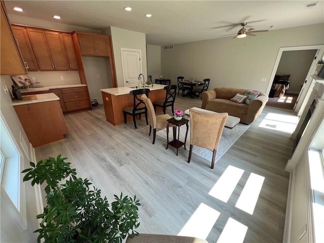 living room with ceiling fan, plenty of natural light, sink, and light hardwood / wood-style flooring