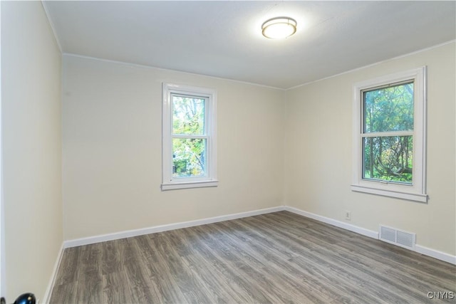 unfurnished room with crown molding, plenty of natural light, and wood-type flooring