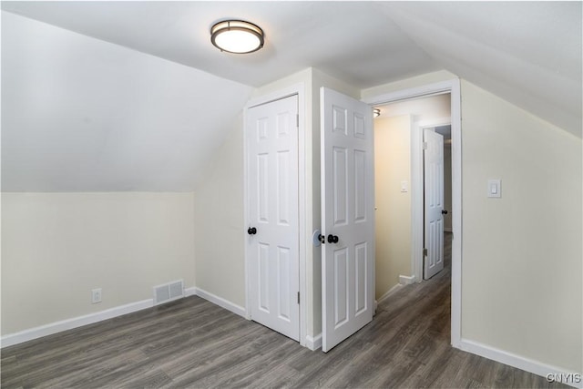 additional living space with dark wood-type flooring and vaulted ceiling