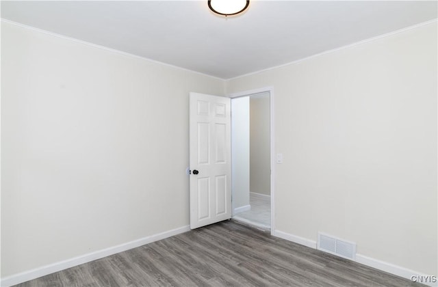 spare room featuring wood-type flooring and ornamental molding