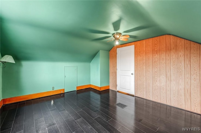 bonus room with dark hardwood / wood-style flooring, wooden walls, and lofted ceiling