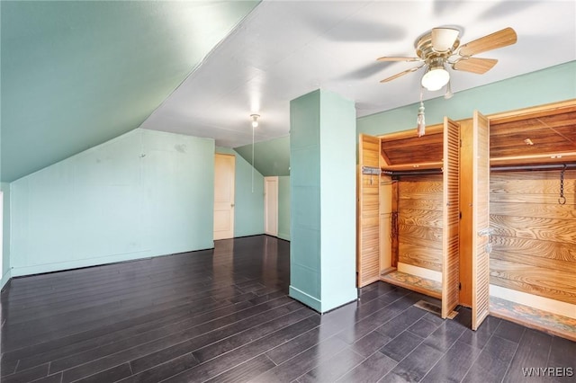 additional living space featuring wood walls, dark hardwood / wood-style flooring, ceiling fan, and lofted ceiling