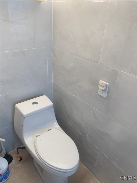 bathroom featuring toilet and tile walls