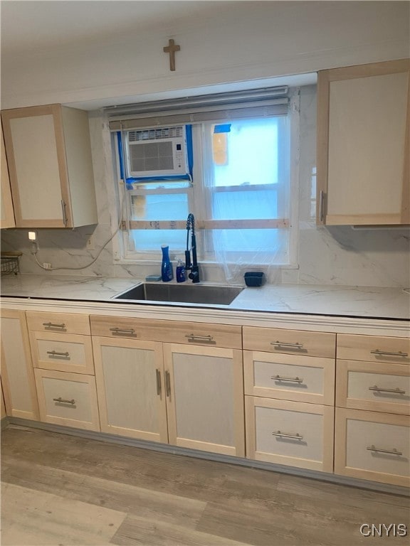 kitchen featuring tasteful backsplash, a wall mounted AC, sink, light hardwood / wood-style flooring, and cream cabinetry