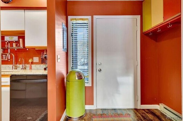 foyer entrance featuring dark wood-type flooring, a baseboard heating unit, and sink