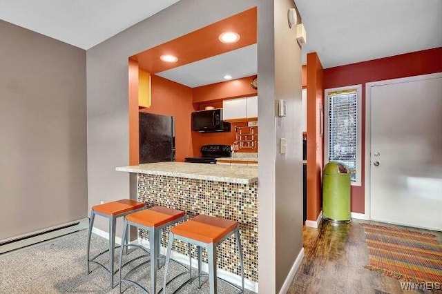 kitchen with black appliances, kitchen peninsula, dark hardwood / wood-style floors, a kitchen bar, and white cabinetry