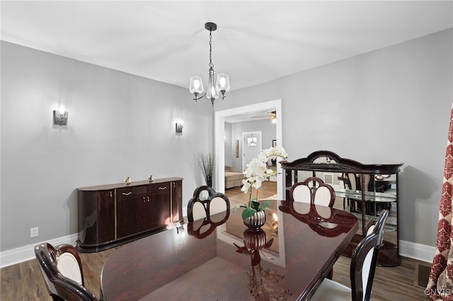 dining area featuring ceiling fan with notable chandelier and dark wood-type flooring