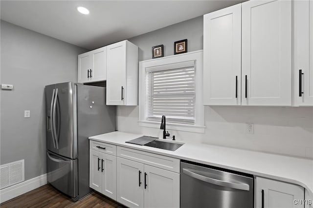 kitchen with dark wood-type flooring, sink, white cabinets, and stainless steel appliances