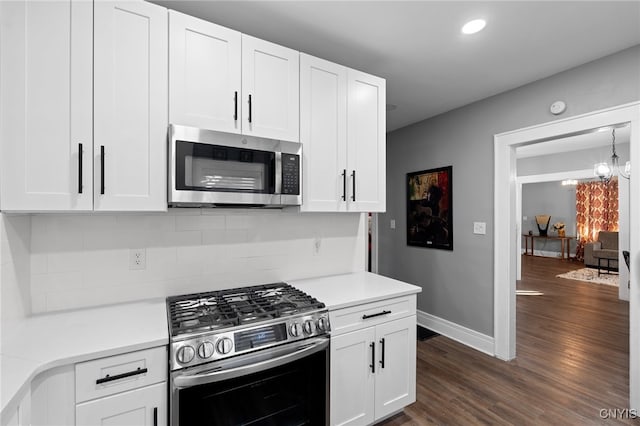 kitchen featuring dark wood-type flooring, appliances with stainless steel finishes, tasteful backsplash, a notable chandelier, and white cabinetry