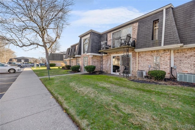 view of property exterior with central AC unit, a balcony, and a yard