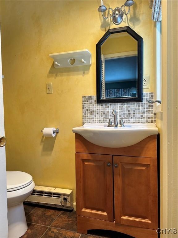 bathroom featuring backsplash, tile patterned floors, vanity, a baseboard heating unit, and toilet