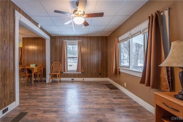 empty room featuring a paneled ceiling, dark hardwood / wood-style floors, and wood walls