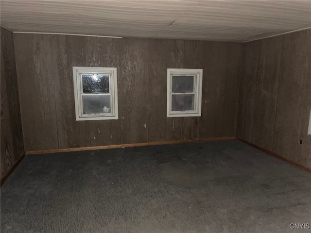 carpeted spare room featuring wood walls