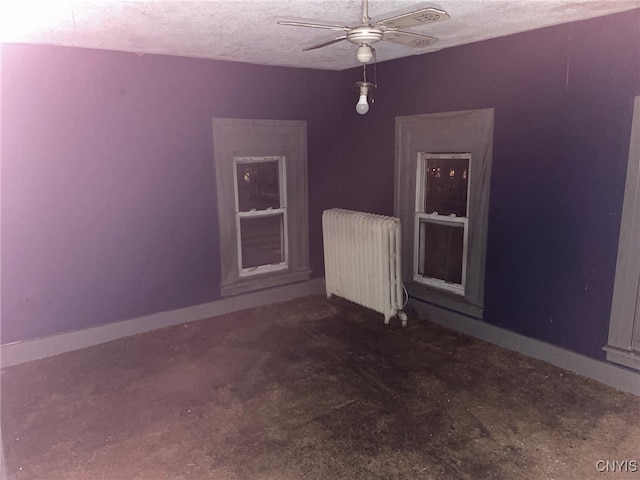 unfurnished room with ceiling fan, radiator heating unit, and a textured ceiling