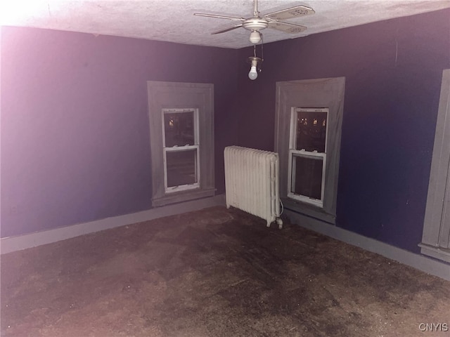 unfurnished room with ceiling fan, radiator heating unit, and a textured ceiling