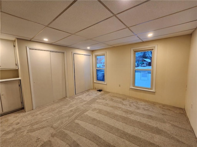 interior space with a drop ceiling and light colored carpet