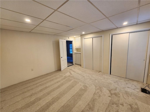 interior space featuring multiple closets, light carpet, and a paneled ceiling