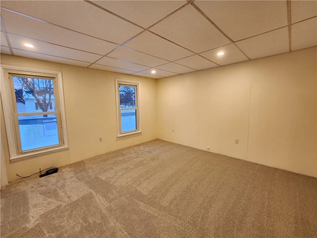 carpeted spare room with a paneled ceiling and a healthy amount of sunlight