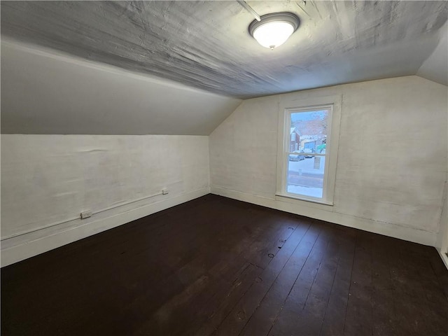 bonus room featuring vaulted ceiling and dark wood-type flooring