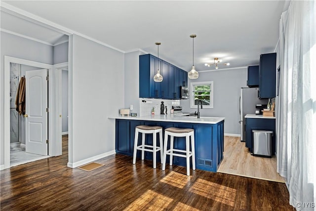 kitchen with kitchen peninsula, a breakfast bar, wood-type flooring, and blue cabinets