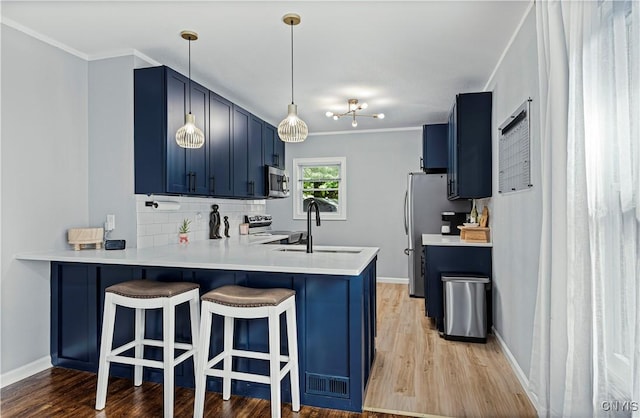 kitchen featuring blue cabinetry, stainless steel appliances, kitchen peninsula, and sink