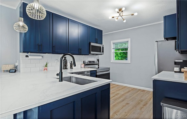 kitchen featuring appliances with stainless steel finishes, crown molding, sink, blue cabinetry, and a chandelier